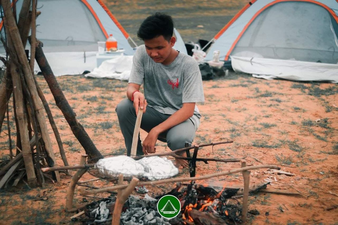 A photo of a young man tending to a fire 