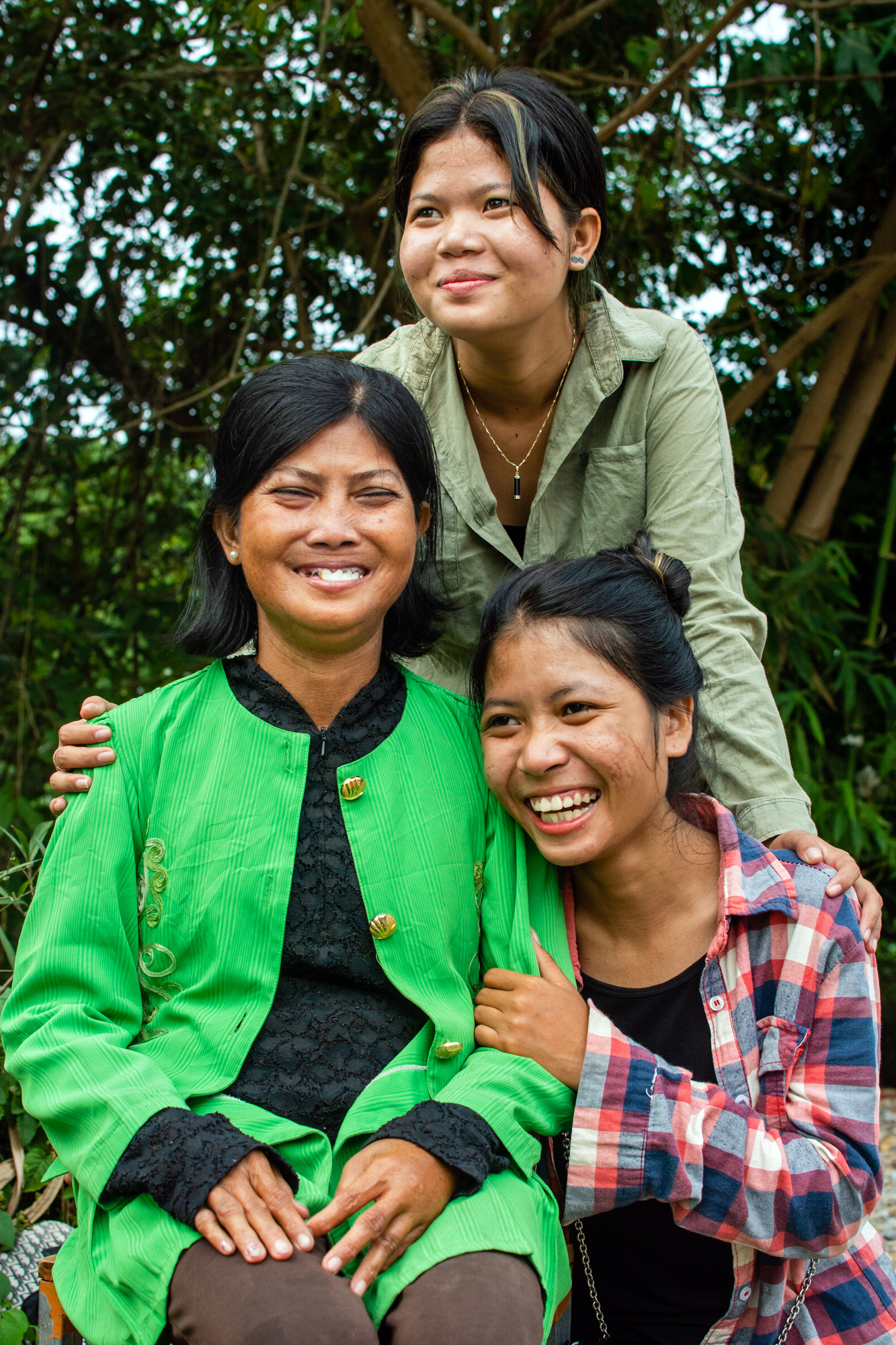 A supportive family of three smiling. A mother and two teenage daughters